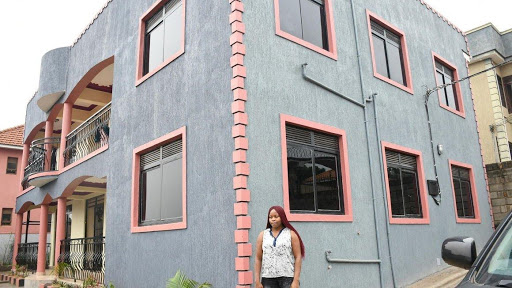 Anna Kebba spent a decade constructing her dream home. Here, she poses outside her home and rental units.